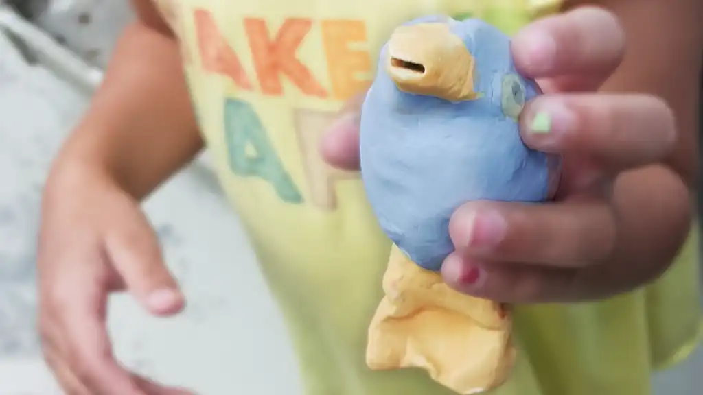 A young artist presenting a ceramic blue-bird.